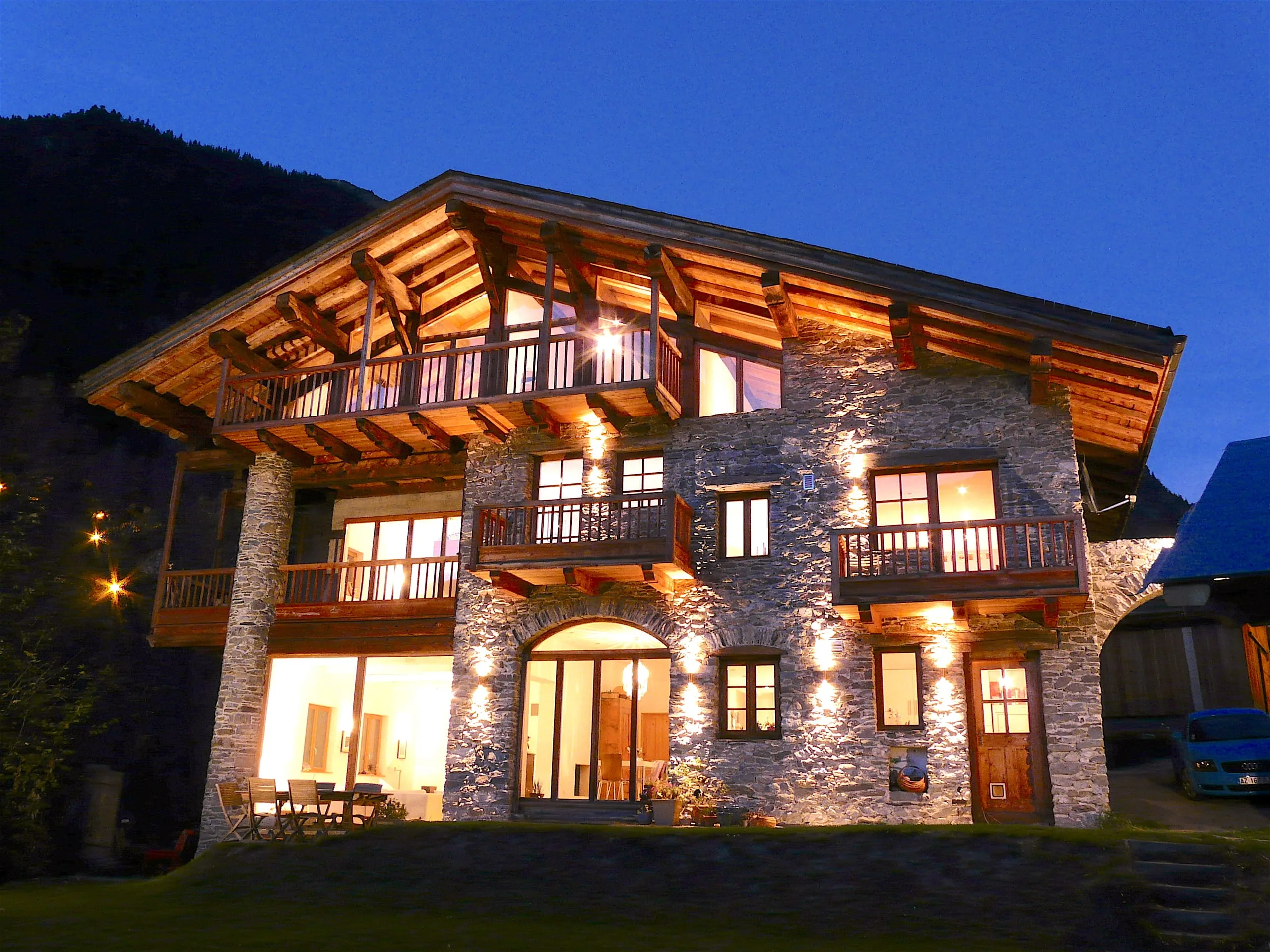 Chalet La Tillette at night, its stone and timber facade lit warmly against fresh snow