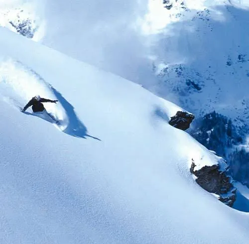 Un snowboardeur soulevant la poudreuse