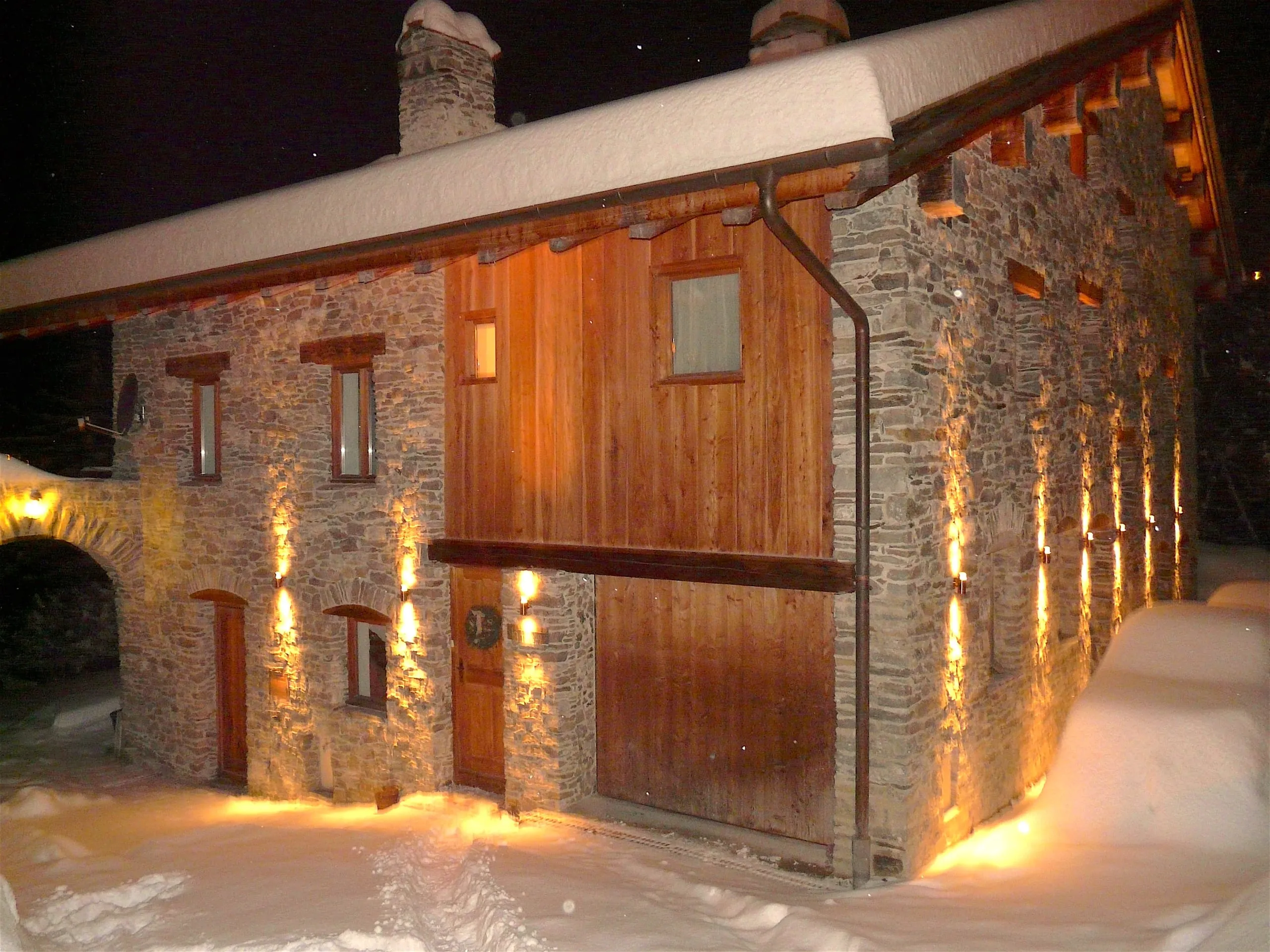 L’entrée du chalet éclairée par une nuit de neige